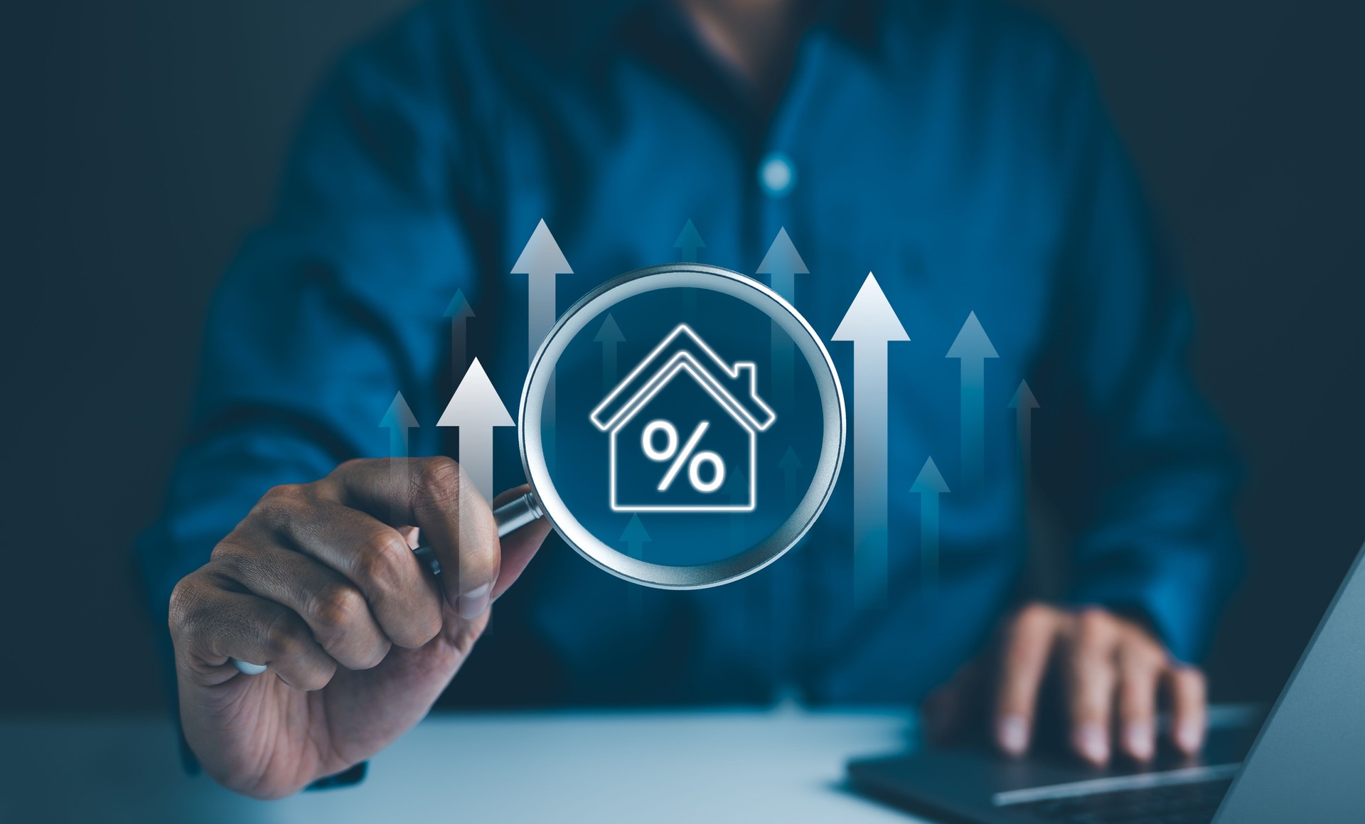 Concept d’investissement immobilier. Un homme d’affaires utilise une loupe pour examiner une icône de maison avec un signe de pourcentage, représentant l’analyse des investissements immobiliers et les tendances du marché.
